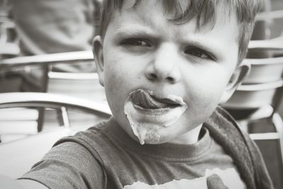Cute boy licking ice cream on his mouth outdoors