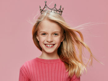 Portrait of young woman standing against pink background