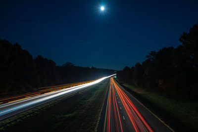 Light trails on road against sky at night