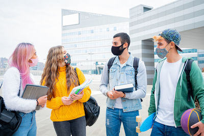 Students with mask discussing while standing in campus
