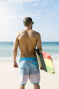 Rear view of shirtless man on beach