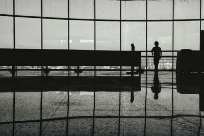 Silhouette boy standing by window at airport
