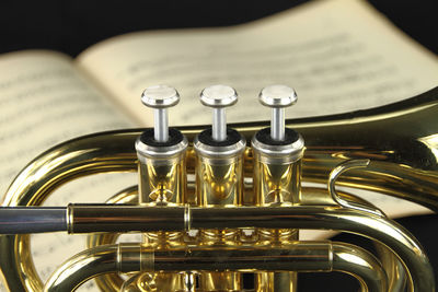 Close-up of trumpet on sheet music against black background