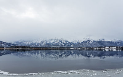 Scenic view of lake by snowcapped mountains against sky