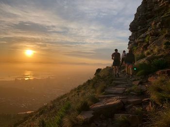 People climbing on mountain during sunset