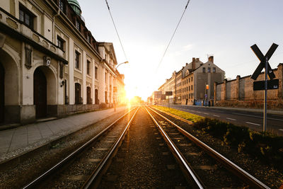 Railroad tracks against sky during sunset in city