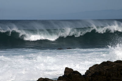 Waves splashing on sea against sky