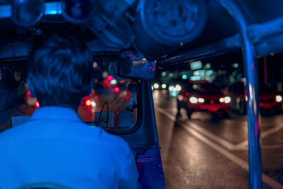 Rear view of man holding illuminated car at night