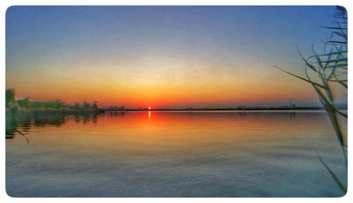 Scenic view of lake against clear sky during sunset