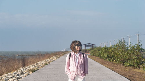 Rear view of woman standing on road against clear sky