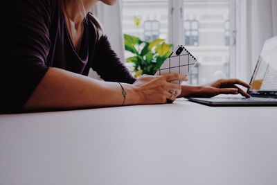 Midsection of woman using mobile phone while sitting on table