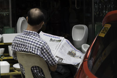 Rear view of man reading newspaper