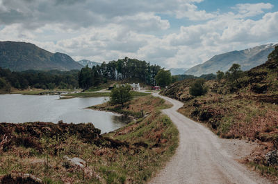 Road amidst plants and mountains against sky