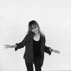 Portrait of young woman standing against white background