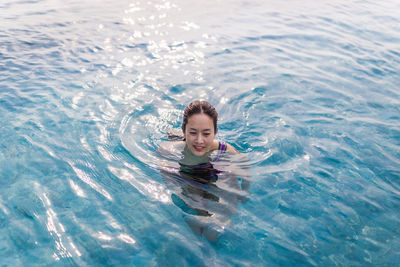 High angle portrait of smiling woman swimming in pool