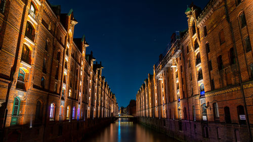 Canal amidst buildings against sky at night