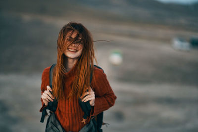 Beautiful young woman standing against blurred background