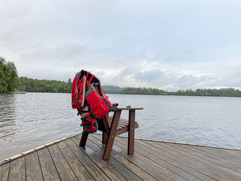 Man sitting on pier over lake against sky