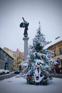 Statue on christmas tree in city against sky during winter