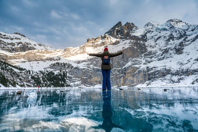 Rear view of person standing on snowcapped mountain against sky