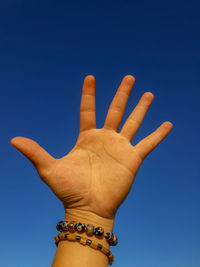 Close-up of hand against blue sky