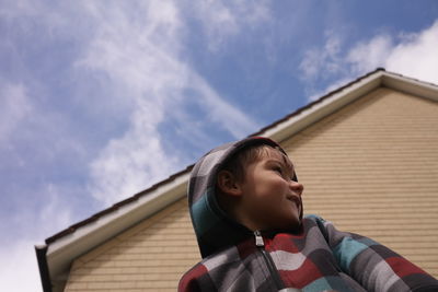 Low angle view of boy looking away against house and sky