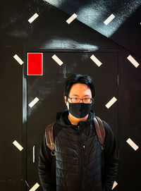 Portrait of young man standing against wall