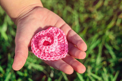 Cropped child holding pink heart shaped woolen crochet 