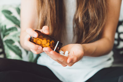 Midsection of woman holding pills