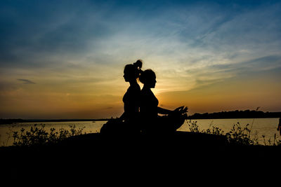 Silhouette men on beach against sky during sunset