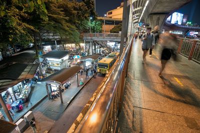 High angle view of crowd on road at night with blurred motion of people on skywalk in bangkok