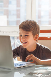 Smiling boy using laptop at table