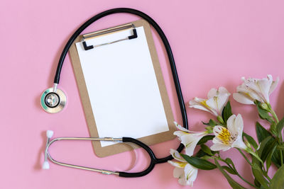 Close-up of stethoscope with flowers on white background