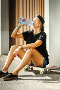 Woman with skateboard sitting in city