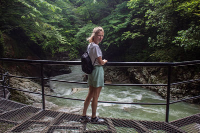 Portrait of woman standing on bridge over river in forest