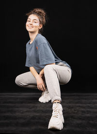 Smiling girl sitting against black background