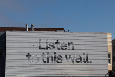 Low angle view of text on building against clear sky