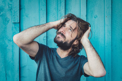 Portrait of young man standing against blue wall