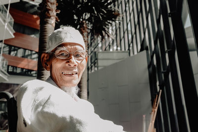 Portrait of smiling senior man wearing skull cap against building