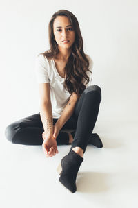 Portrait of young woman sitting against white background