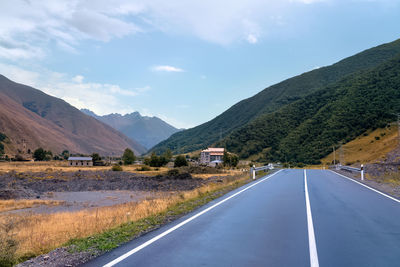 Empty road along landscape and mountains against sky