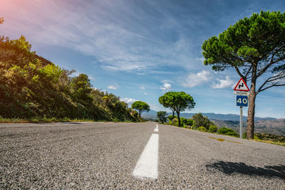 Surface level of road by trees against sky