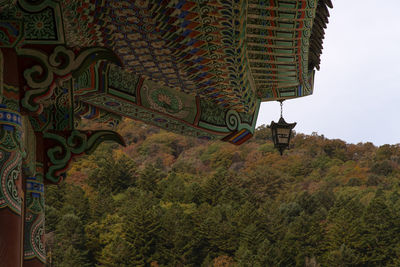 Low angle view of trees and building against sky