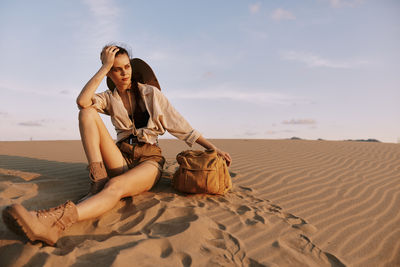 Young woman sitting on sand at beach