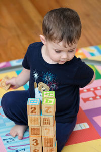 Toddler building a structure out of wooden cubes with alphabet on them