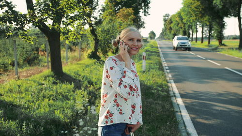 Portrait of young woman talking on phone while standing at roadside