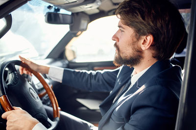 Side view of young man sitting in car