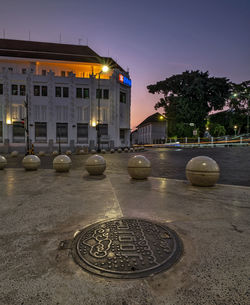 Illuminated buildings by street against sky at night