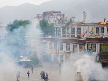 View of barkhor square across the smoke emitted from burners in front of a buddhist temple.