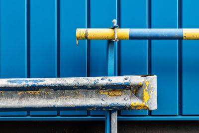 Close-up of rusty metal railing against blue wall